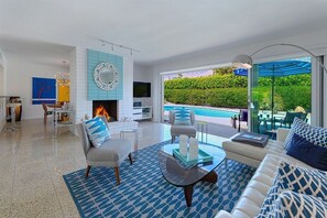 Una sala de estar moderna con chimenea, vista a la piscina y comedor.