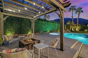 An outdoor patio with a fire pit, seating, and a pool. - Palm Springs Oasis - Palm Springs Perfection: Relax, Play & Recharge in Your Own Oasis (Palm Springs)