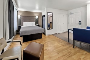 Une chambre d’hôtel comprenant un lit, une table de chevet, une chaise et une petite table avec une autre chaise.