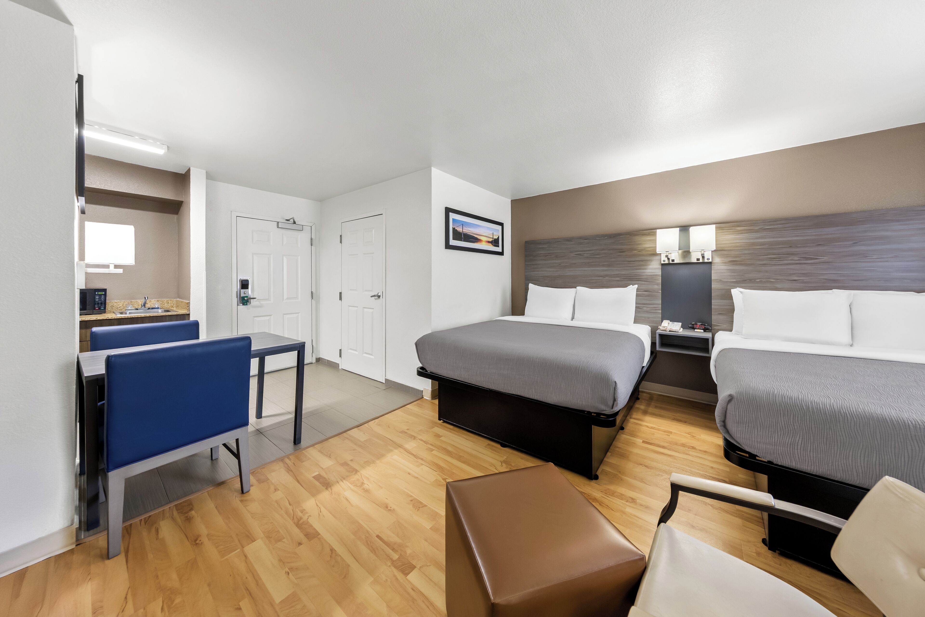 Une chambre d’hôtel avec deux lits, un bureau, une chaise et une petite table.