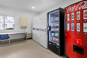 Una habitación con una máquina expendedora llena de bebidas, un escritorio y una ventana que ofrece vistas de edificios.