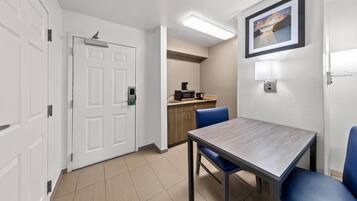 A hotel room with a dining table, chairs, a microwave, and a coffee maker.