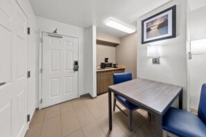 A hotel room with a dining table, chairs, a microwave, and a coffee maker.