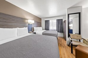 A hotel room with two beds, a desk, a chair, a mirror, and a window with curtains. - Quality Inn Fishers - Indianapolis (Fishers)