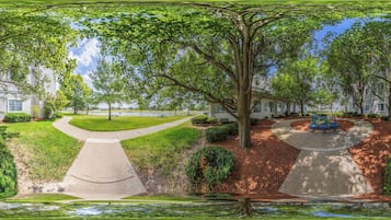 A park with a paved walkway, benches, and a picnic table.