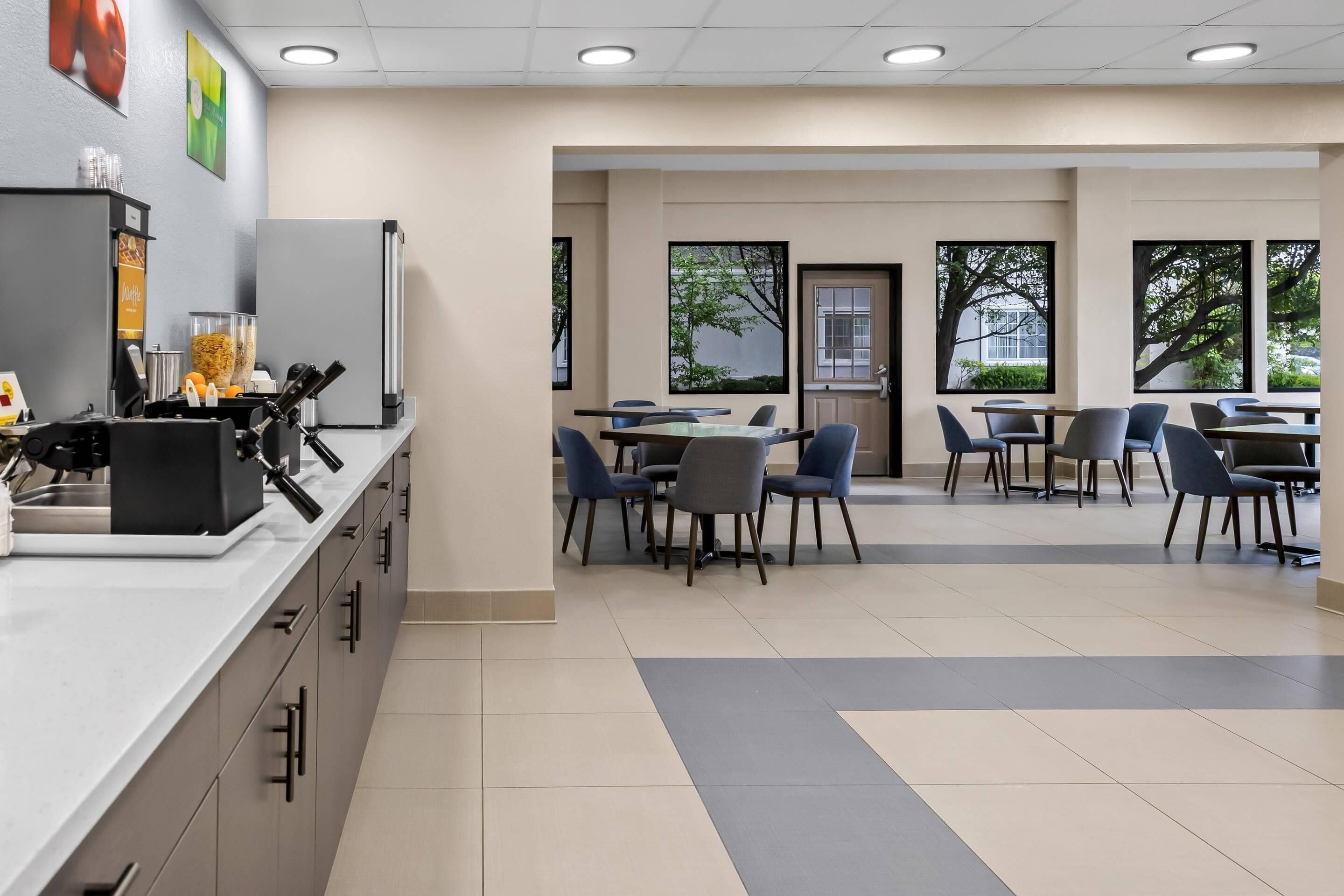 A cafeteria with a long counter, multiple tables, and chairs.
