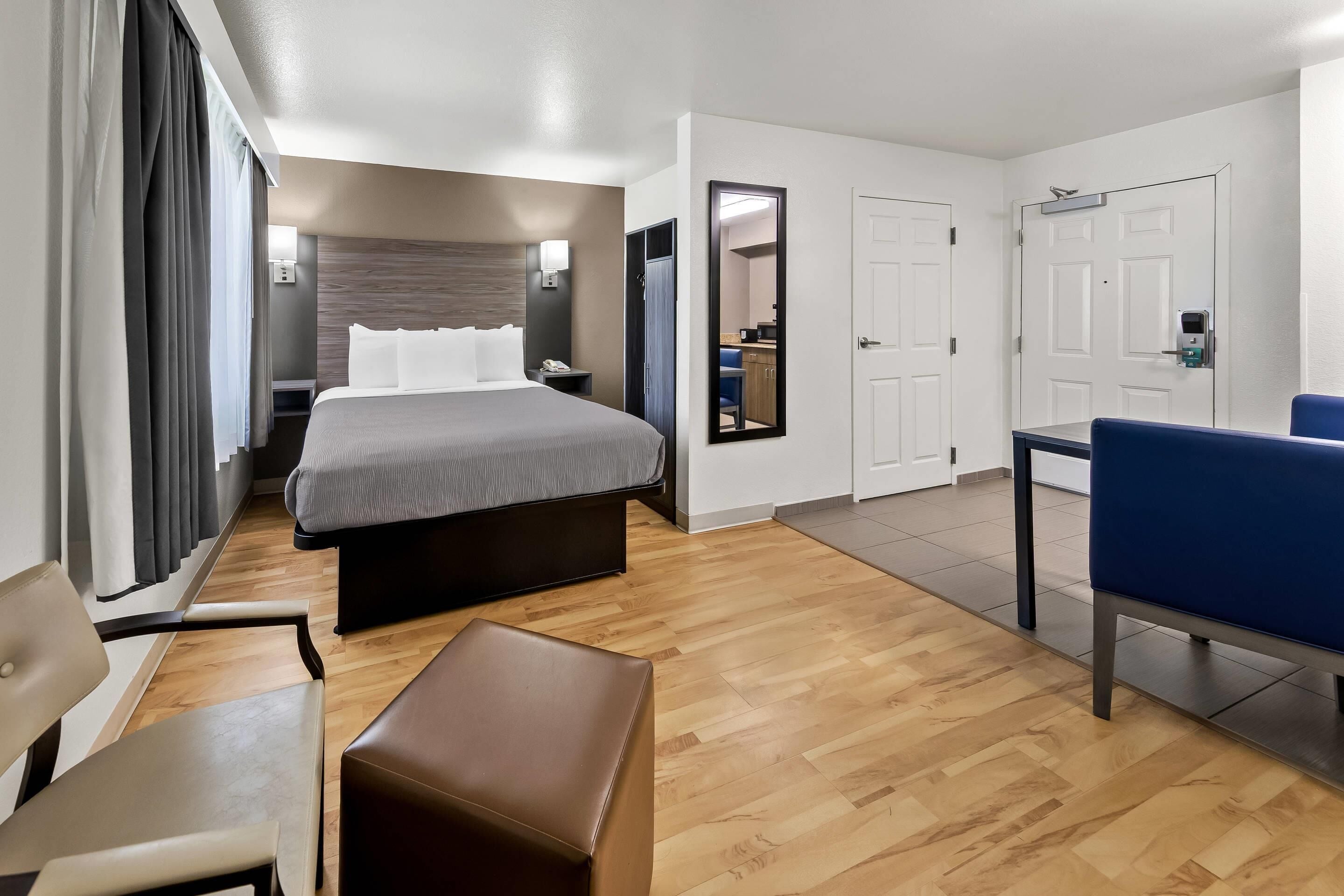 Una habitación de hotel con cama, escritorio, silla, mesita y espejo.