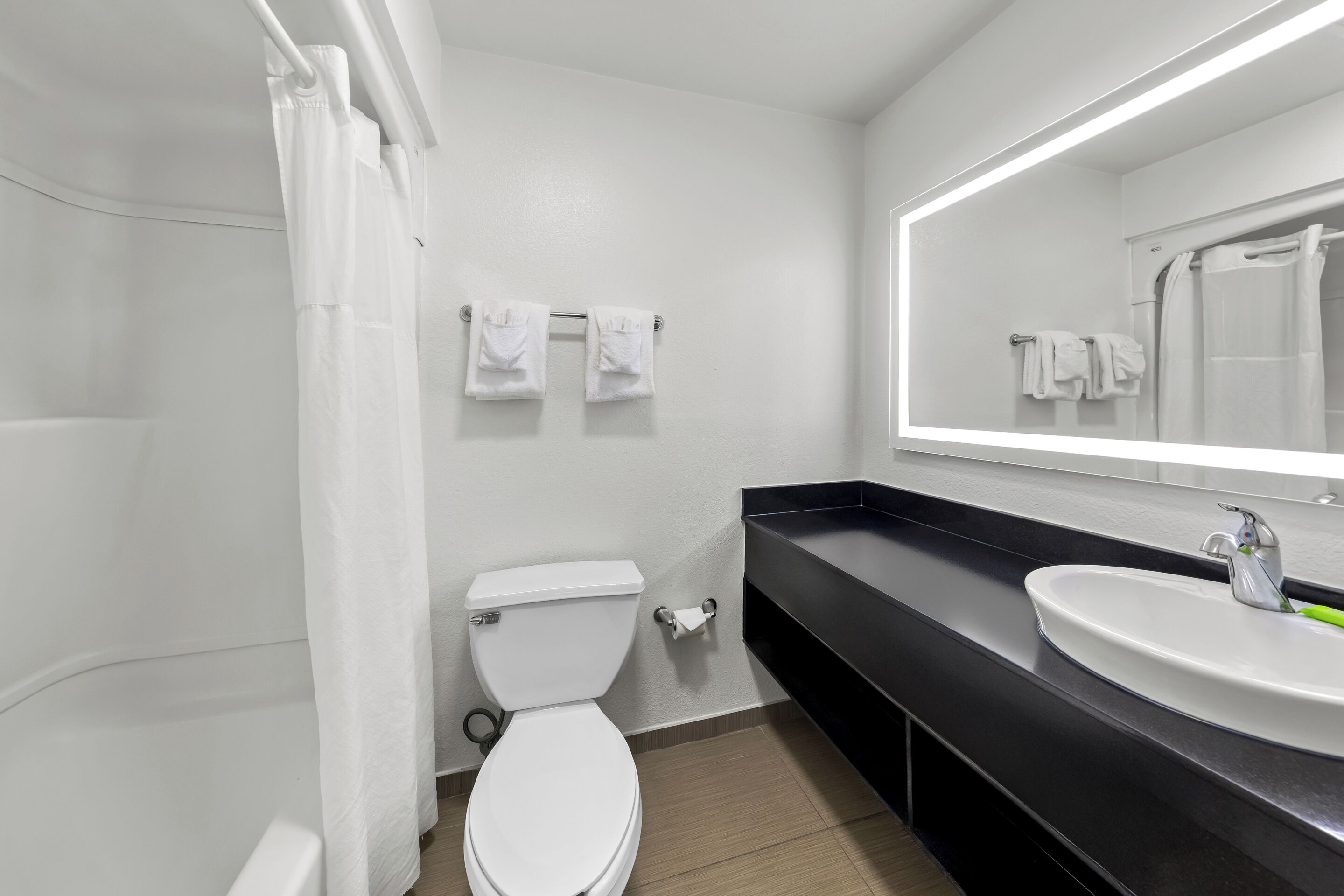 A modern bathroom with a toilet, sink, and a large mirror.