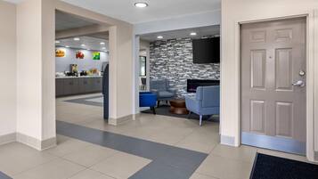 A modern hotel lobby with a reception desk, seating area, and a stone accent wall.