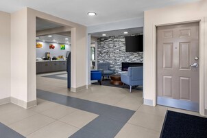 Un moderno vestíbulo de hotel con una recepción, zona de estar y una pared decorativa de piedra.
