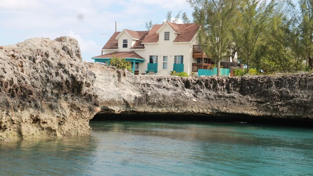 A house with a view of the ocean and a rocky cliff.
