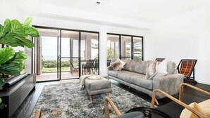 Una sala de estar moderna con un sofá gris, una mesa de centro y una planta grande.