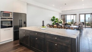 Una cocina moderna con armarios oscuros, una isla de mármol y un comedor con vistas.