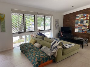 Relax in this stylish living room with a large sofa, flat-screen TV, and vibrant artwork.