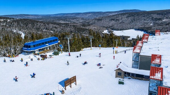 A ski resort with a blue bus, ski lifts, and a snow-covered landscape.
