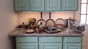 Une cuisine avec des armoires de couleur turquoise, un plan de travail en granit, ainsi que divers ustensiles de cuisine et accessoires.