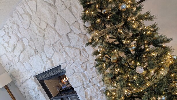 Un mur de pierres, une cheminée et un sapin de Noël décoré.