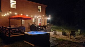 Un espace patio aménagé avec un jacuzzi, du mobilier d’extérieur et des guirlandes lumineuses.