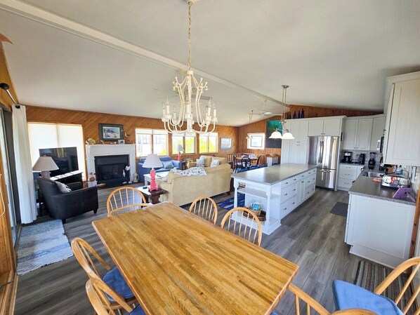 A spacious living area with a fireplace, a dining table, and a kitchen with white cabinets.