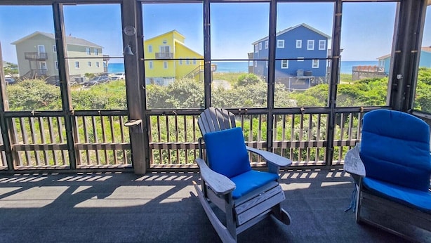 A covered outdoor area with a view of houses and the ocean.