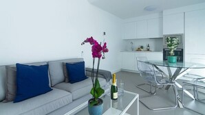 Ein modernes Wohnzimmer mit einer Couch, einem Glastisch und einer Vase mit Blumen.