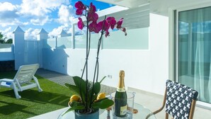 Eine Terrasse mit Tisch, einer Topfpflanze, einer Champagnerflasche und einem Stuhl.