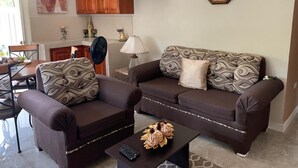 A living room with a sofa set, a coffee table, and a remote control.