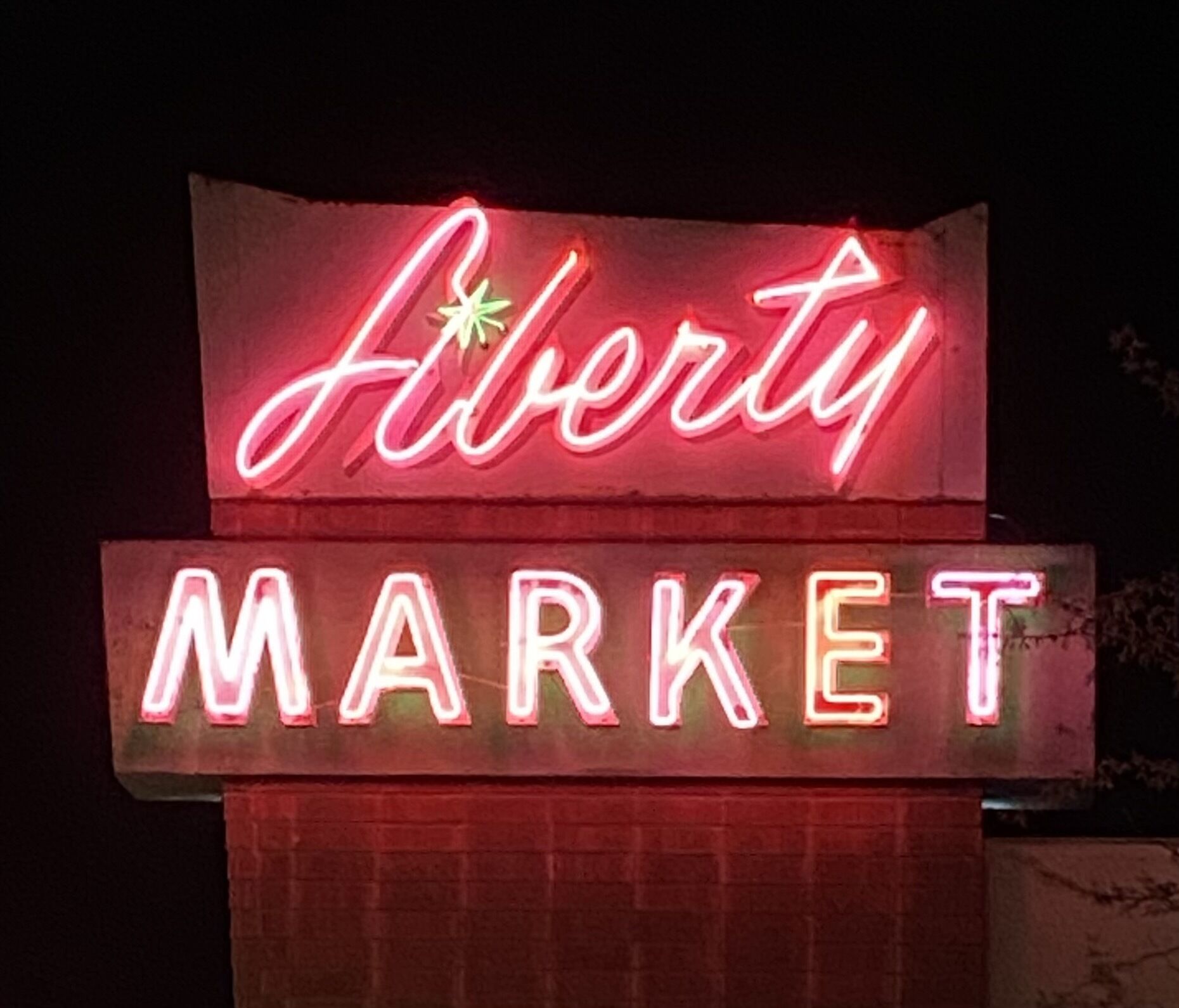 A neon sign for 'Alberta Market' at night.