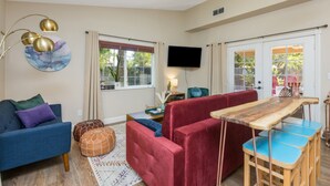A living room with a blue sofa, red armchair, and a wooden coffee table. - POOL OASIS! Super Reviews! EV Charger/1BR King/Wash/Dryer/Kitchenette/Sleeps 4 (Gilbert)