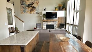 A modern kitchen with a large island, a dining table, and a built-in fireplace.