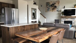 A modern kitchen with a wooden island, stainless steel appliances, and a dining area with a large table and chairs.