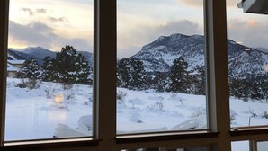 A view through a window of a snowy landscape with mountains in the background.