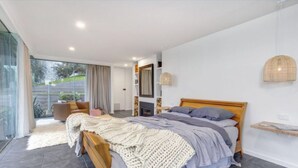 A modern bedroom with a large bed, a fireplace, and a view of the outdoors.