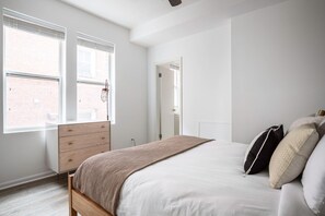 Cozy retreat with a single bed, dresser, and windows with blinds.