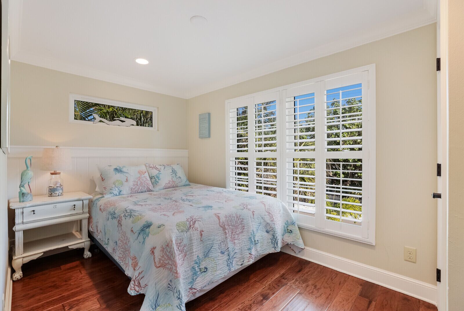 A bedroom with a bed, nightstand, and window with shutters.