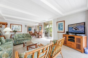 Una sala de estar con televisor, muebles y vista al exterior.