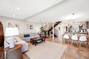 A spacious living area with a sofa, coffee table, and dining table.