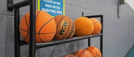 Uma estante com várias bolas de basquete encostadas na parede.