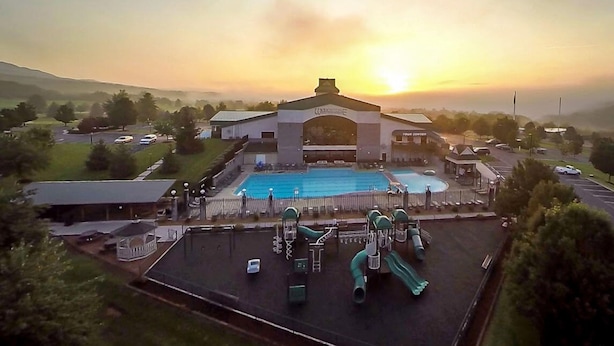 A swimming pool with slides, a parking lot, and a building with a sign that reads "TOUR CENTER".