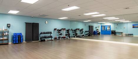 Un gimnasio amplio con equipo de levantamiento de pesas y una pared azul.