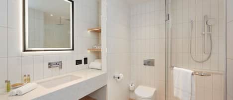 A modern bathroom with a large mirror, a sink, a toilet, and a glass-enclosed shower area.
