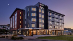 A modern hotel with a prominent Hilton Garden Inn sign, large windows, and a well-lit entrance.