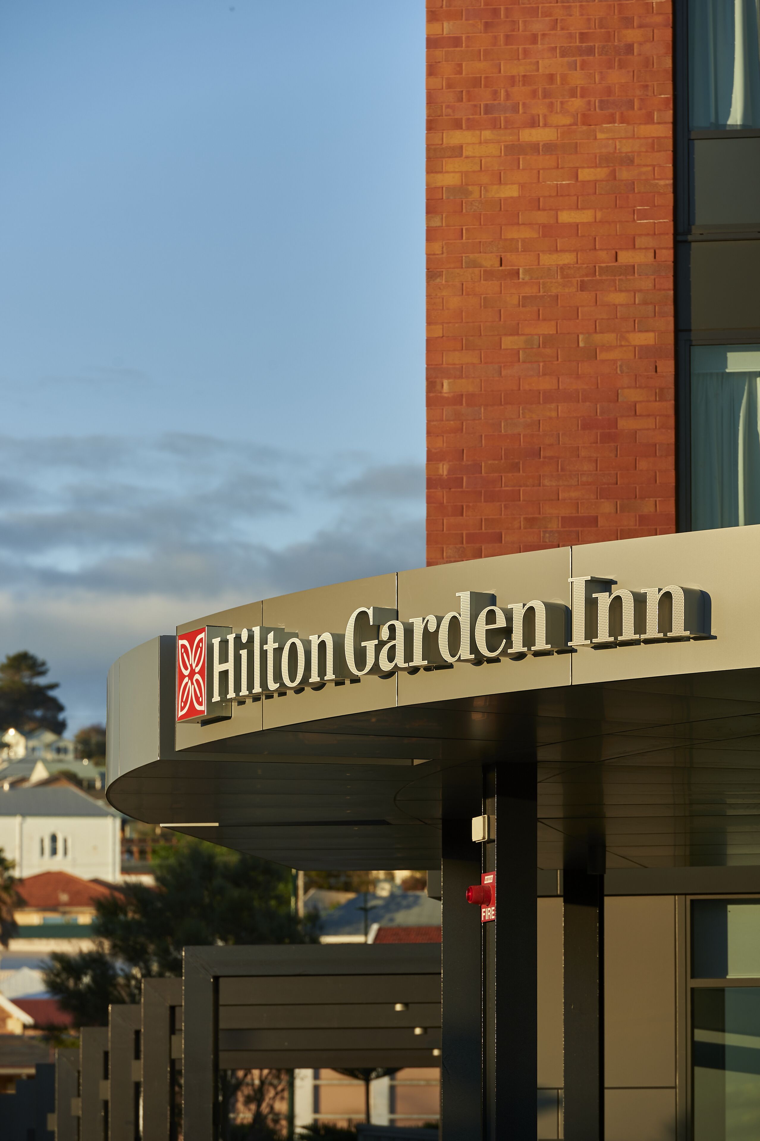 A Hilton Garden Inn sign with a clear view of the building's entrance and a fire hydrant nearby.