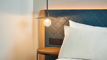 A neatly made bed with a wooden headboard, a bedside table, and a hanging light fixture.