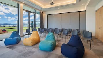 A modern conference room with a large screen, rows of chairs, and bean bags.