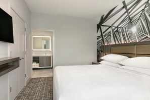 A hotel room with a bed, a television, a mirror, and a bathroom. - Embassy Suites by Hilton Atlanta Midtown (Atlanta)