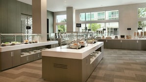 A modern hotel kitchen with a buffet setup, including glass display cases and a variety of food items. - Embassy Suites by Hilton Atlanta Midtown (Atlanta)