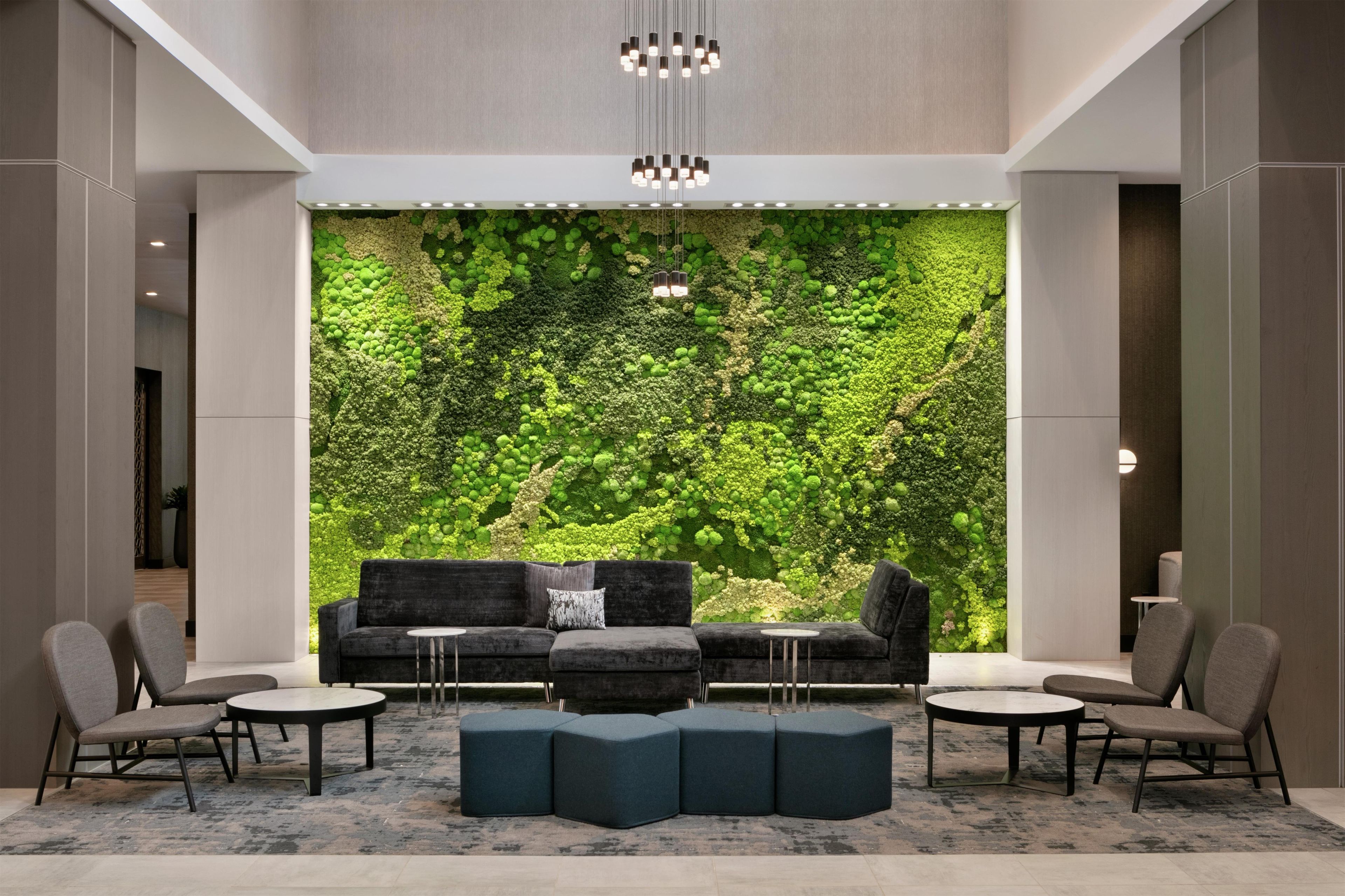 A modern lobby with a green wall, seating area, and a chandelier.