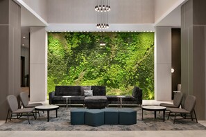A modern lobby with a green wall, seating area, and a chandelier. - Embassy Suites by Hilton Atlanta Midtown (Atlanta)