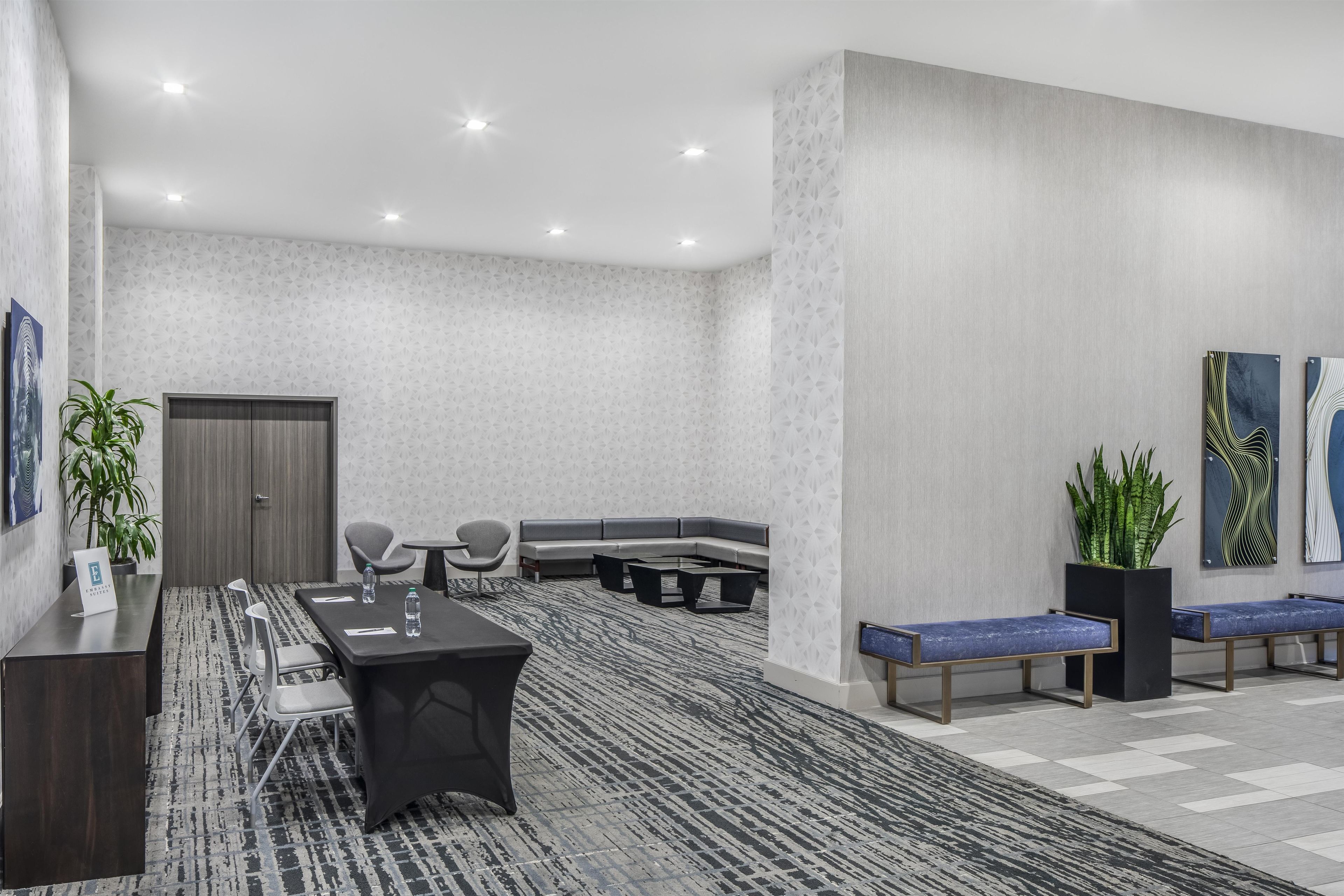 A modern conference room with a long table, chairs, a sofa, and a bench.